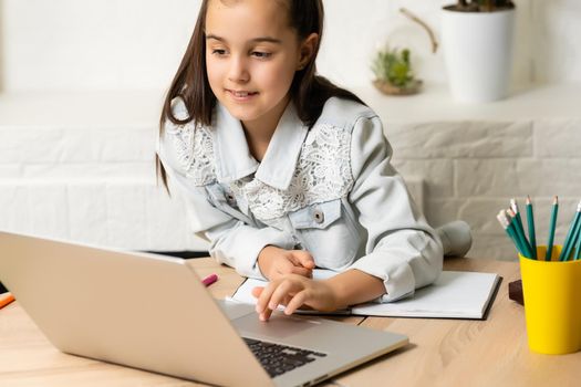 Student little school girl homework on laptop computer silver background