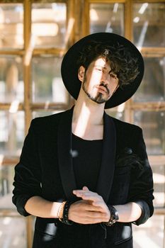 Portrait of a young man in a black hat on the background of a wooden window. High quality photo