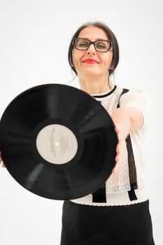 Studio photo of middle aged woman starting getting grey-haired wearing black and white clothes with vinyl record in hands on white background, middle age sexy lady, happy life concept.