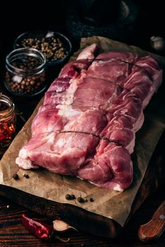 Raw pork loin joint on cutting board with different spices