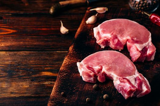 Two raw pork loin steaks on chopping board