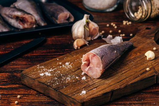 Hake carcasses on cutting board with spices and vegetables