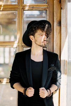 Young man in a black hat on the background of a wooden window. High quality photo