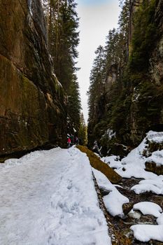 Small footbridge over mountain river between high rocks as path to waterfall