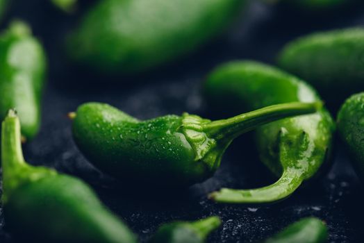 Close Up of Ripe Green Jalapeno Peppers on Dark Concrete Background