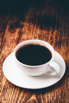 Black coffee in white cup over wooden surface