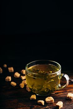 Green tea with brown tea sugar on a wooden background