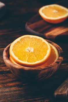 Sliced orange in a wooden bowl in rustic setting