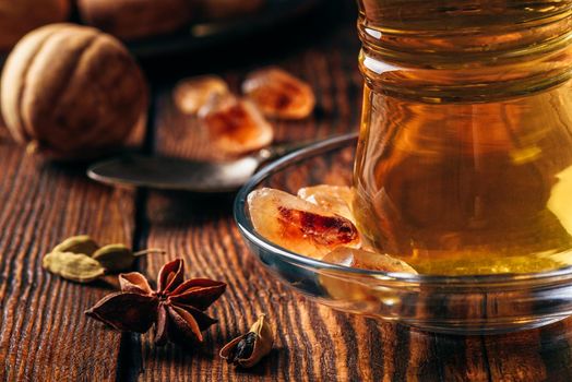 Spiced tea with star anise, cardamom and dried lime in oriental glass over wooden surface