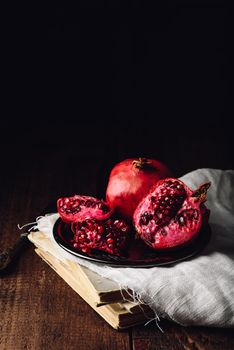 Pomegranate fruit on metal plate over old books