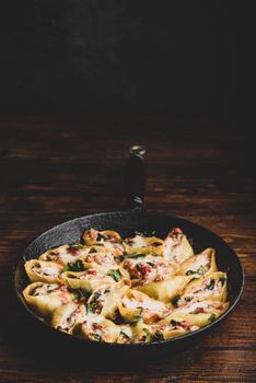 Skillet of baked jumbo shells pasta stuffed with ground beef, spinach and cheese