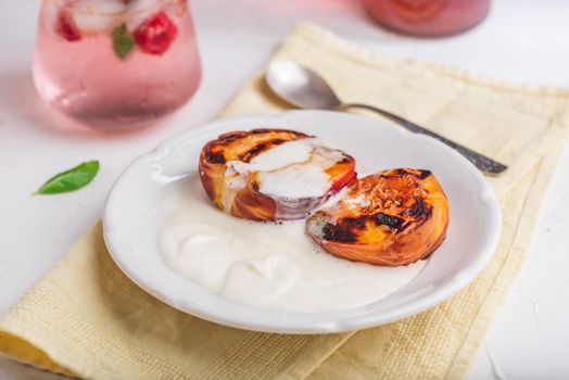 Oven Baked Peaches with Brown Sugar and Whipped Heavy Cream on White Plate and Glass of Raspberry and Mint Infused Water