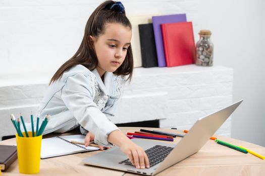 Student little school girl homework on laptop computer silver background