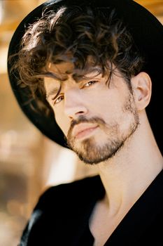 Young man in a black hat against the background of a window. Portrait. High quality photo