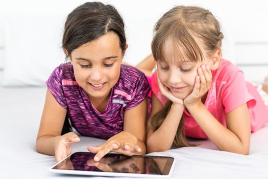 people, children, technology, friends and friendship concept - girls looking to tablet pc computers at home.