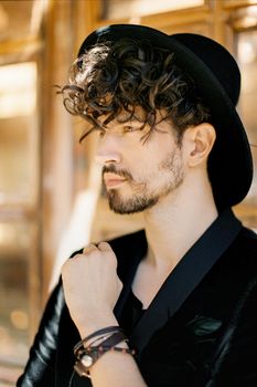 Profile of a young man in a black hat against the background of a window. Portrait. High quality photo