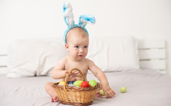 happy caucasian baby girl six months old wearing bunny ears headband.