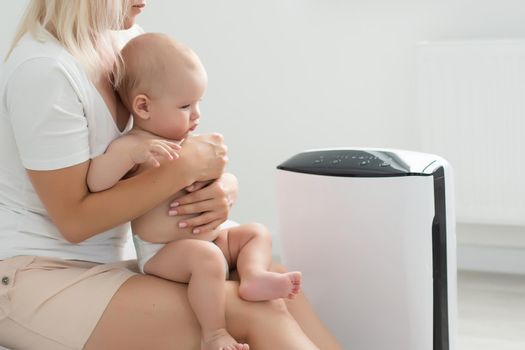 mother and baby near air purifier at home