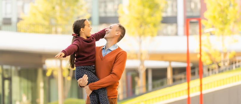 Happy father and daughter walking together in park on an autumns day.