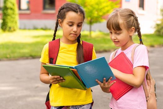 Portrait of two girls with school bags after lesson in school.