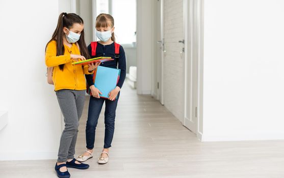 Two pupils friends in protective masks with backpacks. day at school concept.