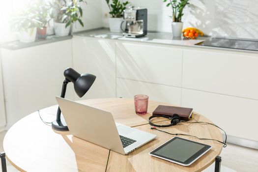 Working from home - a laptop and an organizer on a kitchen table with kitchen in the background.