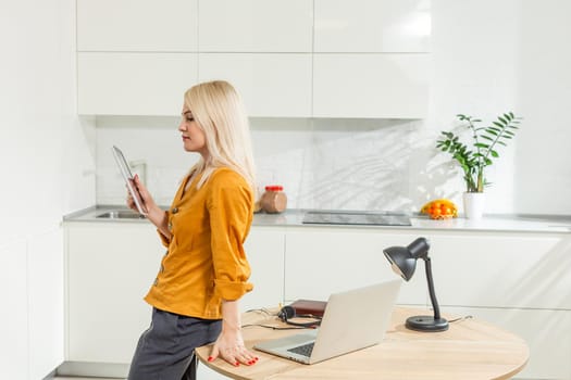 Beautiful caucasian woman working on laptop. Kitchen background.