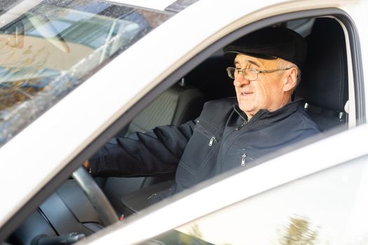 Smiling happy elderly man in the new car.