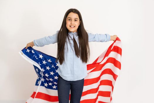 Beautiful patriotic little girl with the American flag held in her outstretched hands.