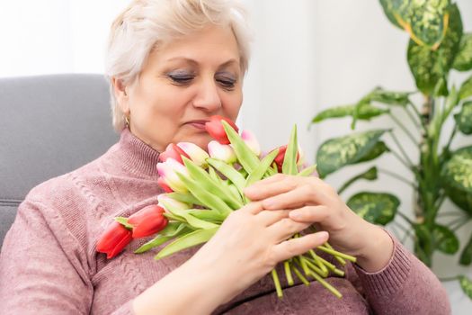 Grandmother holding bouquet of flowers, smiling.