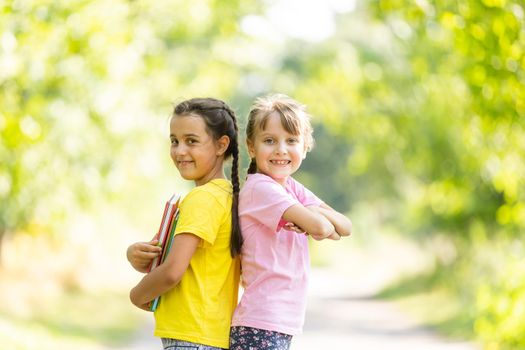 Two happy girls walking and talking each other in a campus.