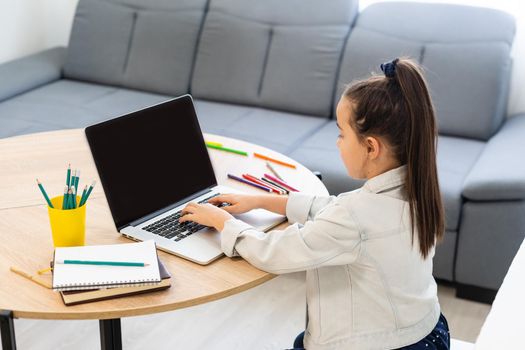 Little girl attending to online e-learning platform class from home while school has been closed during coronavirus outbreak.