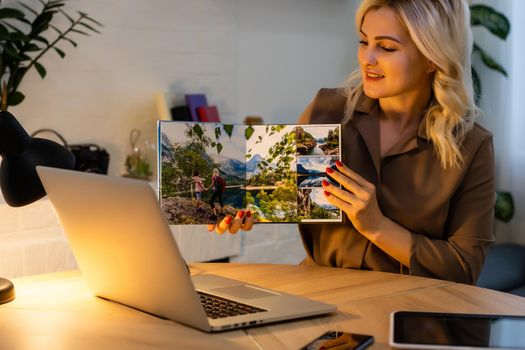 woman holding and presenting photobook near laptop
