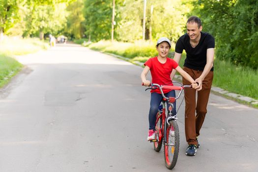 loving father teaching daughter to ride bike.