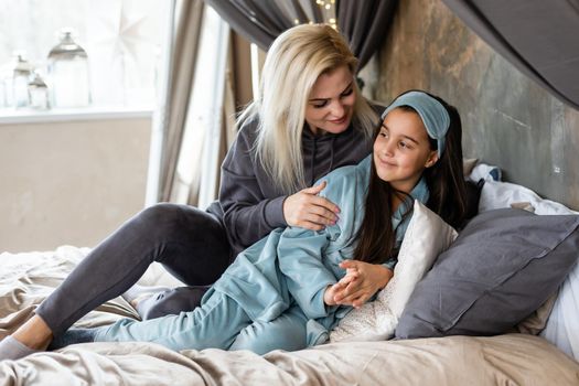 Woman and young girl lying in bed smiling.