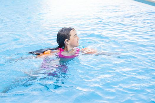 Pretty little girl swimming in outdoor pool and have a fun.