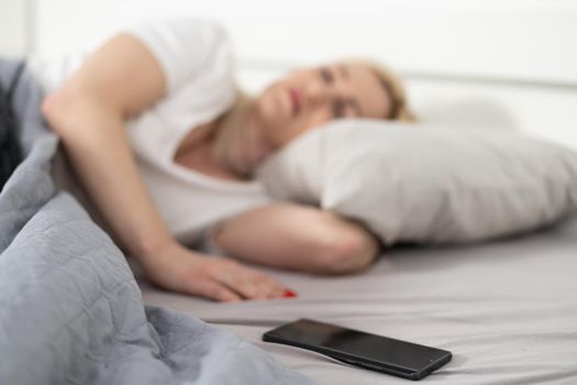 Morning with gadget. Overhead of beautiful young woman lying on the bed smartphone. Top view.