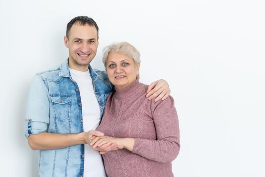 family, generation and people concept - happy smiling senior mother with adult son hugging at home.