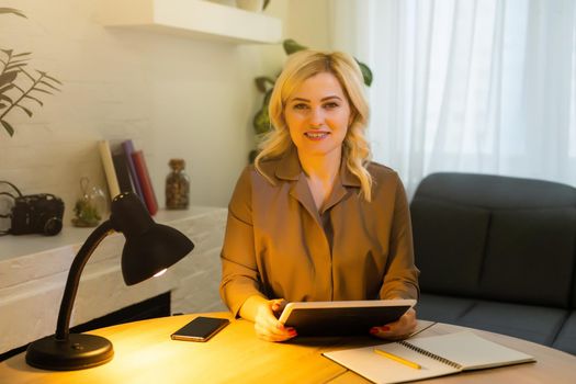 Portrait of a cheerful businesswoman sitting at the table in office and looking at camera
