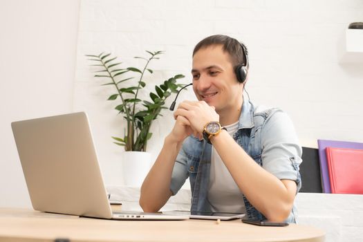 Happy young man smiling, as he works on his laptop to get all his business done early in the morning