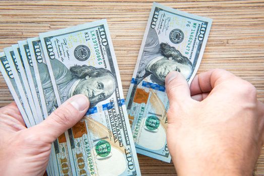 Mans hands hold and count hundred dollar banknotes Close up.