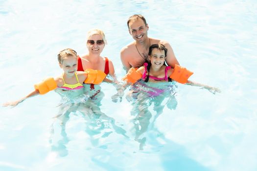 Happy family playing in swimming pool. Summer vacation concept.