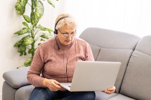 The elderly woman writes on the computer.