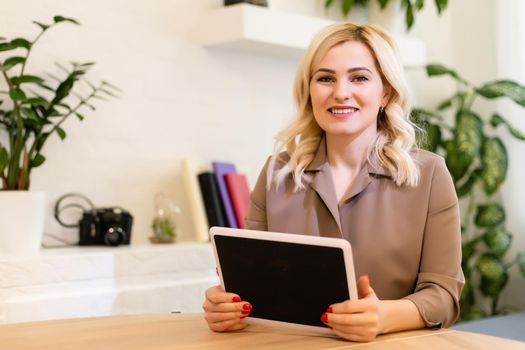 A happy woman girl works remotely from home and communicates via video call with friends and relatives in her office. Distance learning and work online. Using the tablet