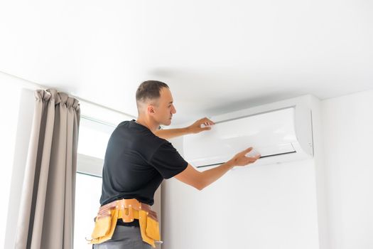 Rear View Of A Man Cleaning Air Conditioning System.