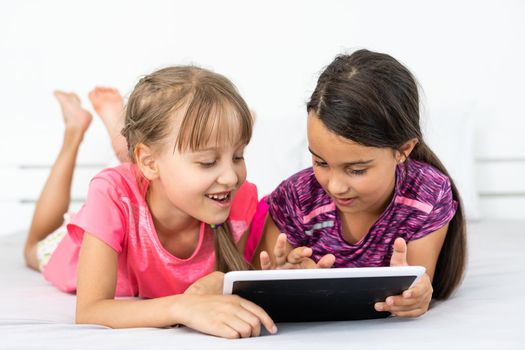 people, children, technology, friends and friendship concept - girls looking to tablet pc computers at home.