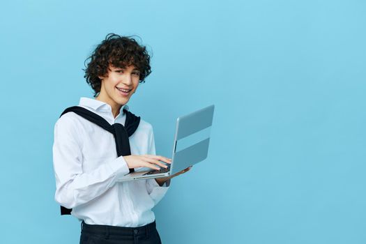 curly guy with laptop internet in a white shirt with a sweater isolated backgrounds. High quality photo