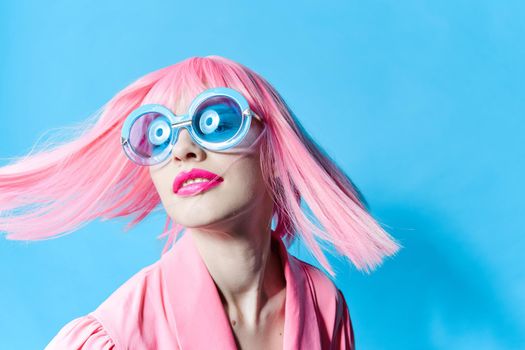 pretty woman in blue glasses wears a pink wig isolated background. High quality photo