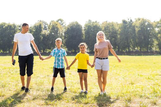 Happy family walking in field and holding hands.