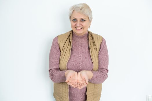 portrait of senior woman gesturing offer with hand over white background.